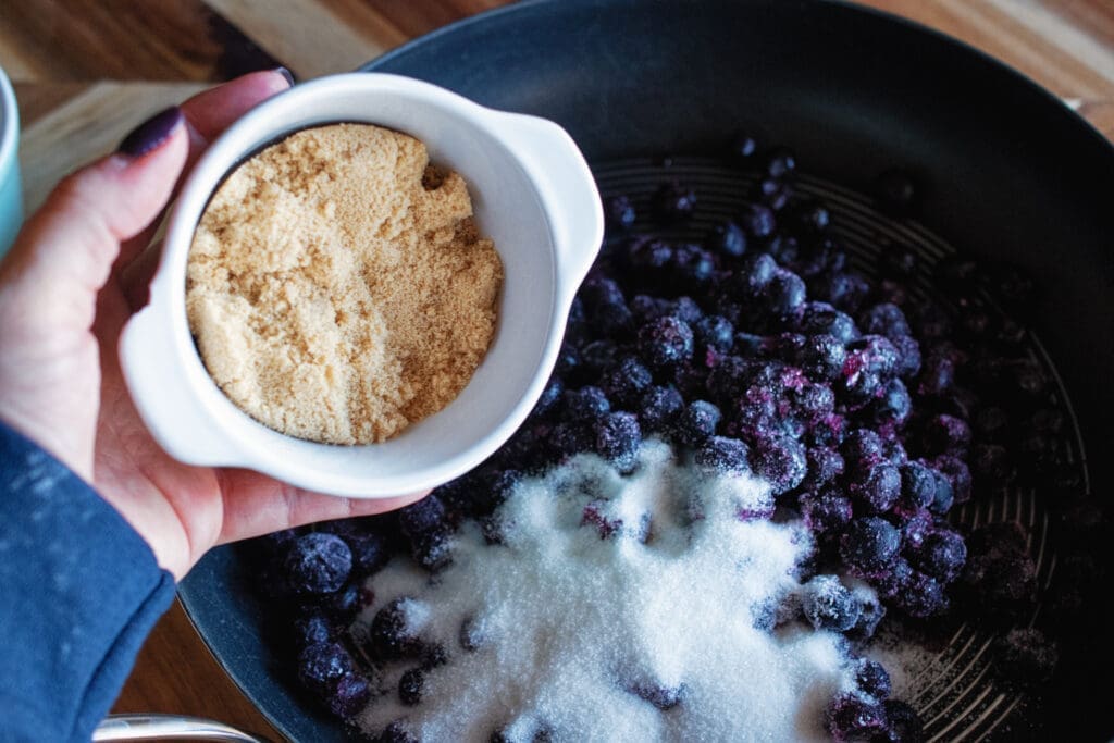 adding brown sugar to blueberry filling
